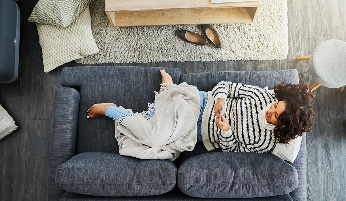 woman laying on the couch with her phone