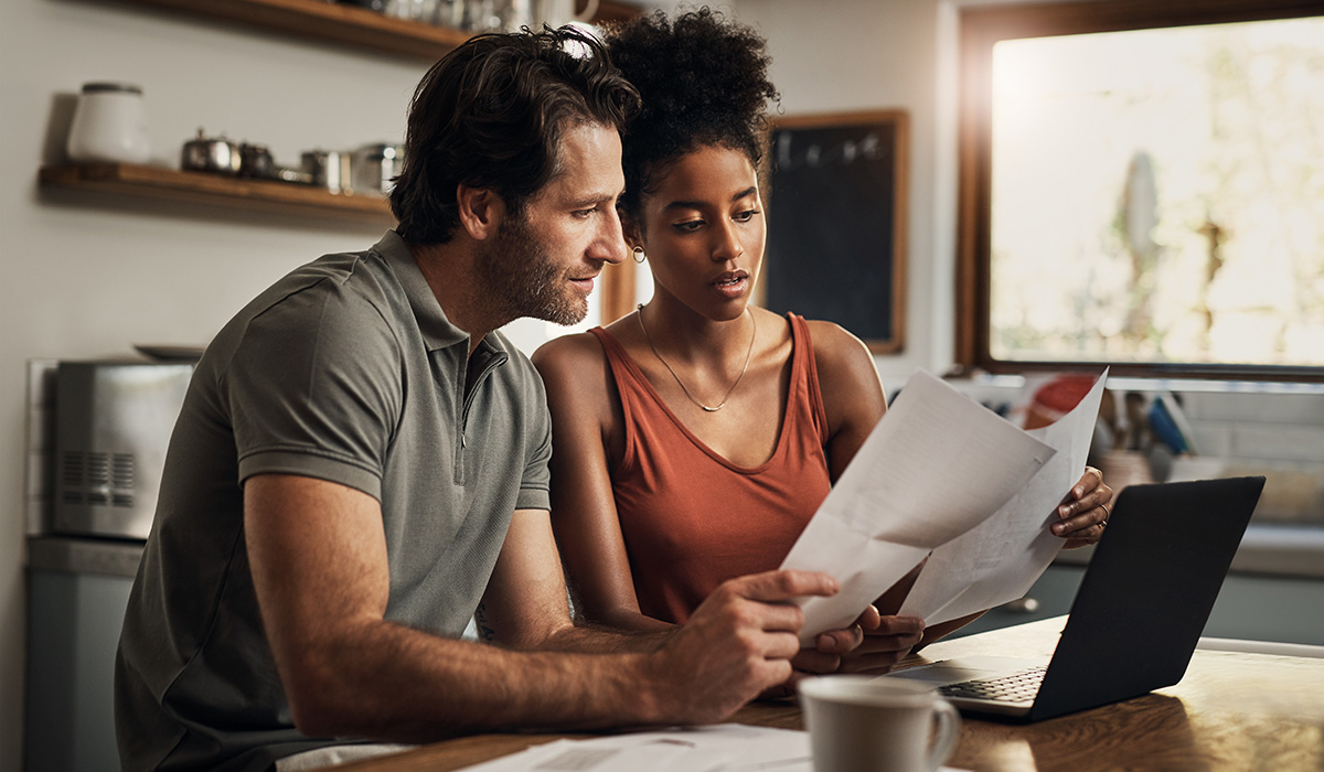 couple looking at paperwork and working on their laptop